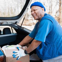 Man in a beanie unloading items from a car trunk